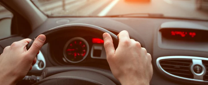 driving on highway road, closeup hands of car driver on steering wheel, road trip at sunset